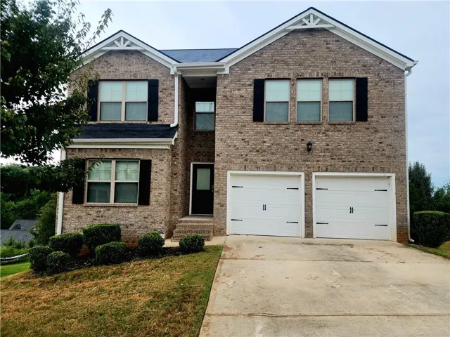 Brick exterior with white gables, a two-car garage, and a concrete driveway