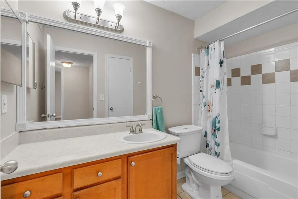 Full bath with vanity, light tile patterned floors, and shower / bathtub combination with curtain