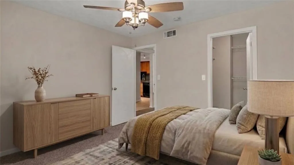 Bedroom with light colored carpet, ceiling fan, and a walk in closet