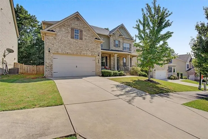 Brick and siding exterior with a two-car garage, concrete driveway, and front porch