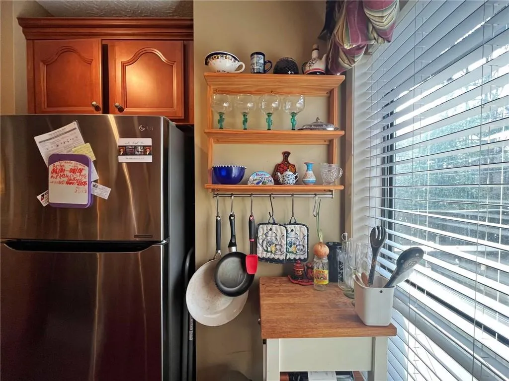 Kitchen featuring freestanding refrigerator, open shelves, and brown cabinets