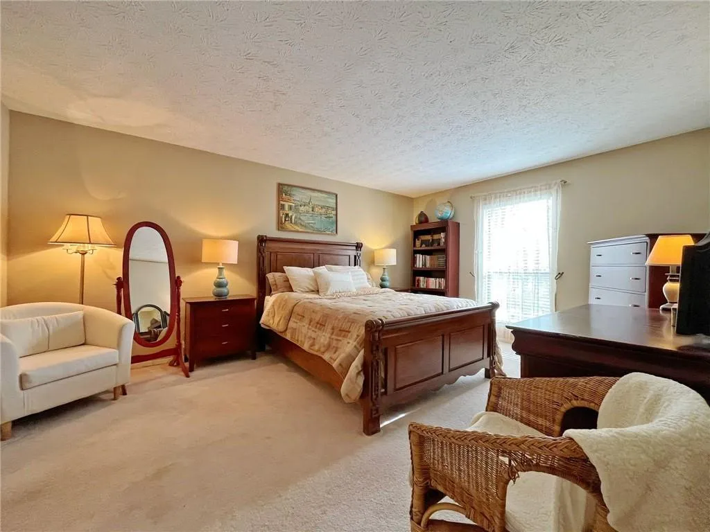 Carpeted bedroom with a textured ceiling and access to exterior