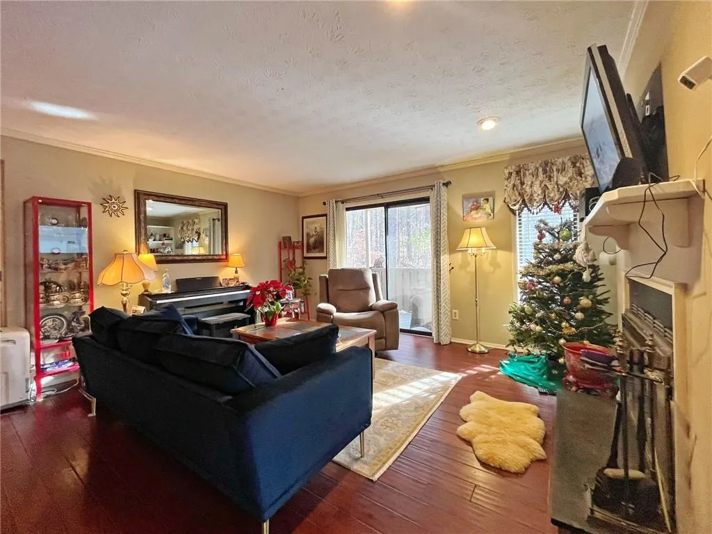 Living area featuring ornamental molding, a fireplace, dark wood-style flooring, and a textured ceiling