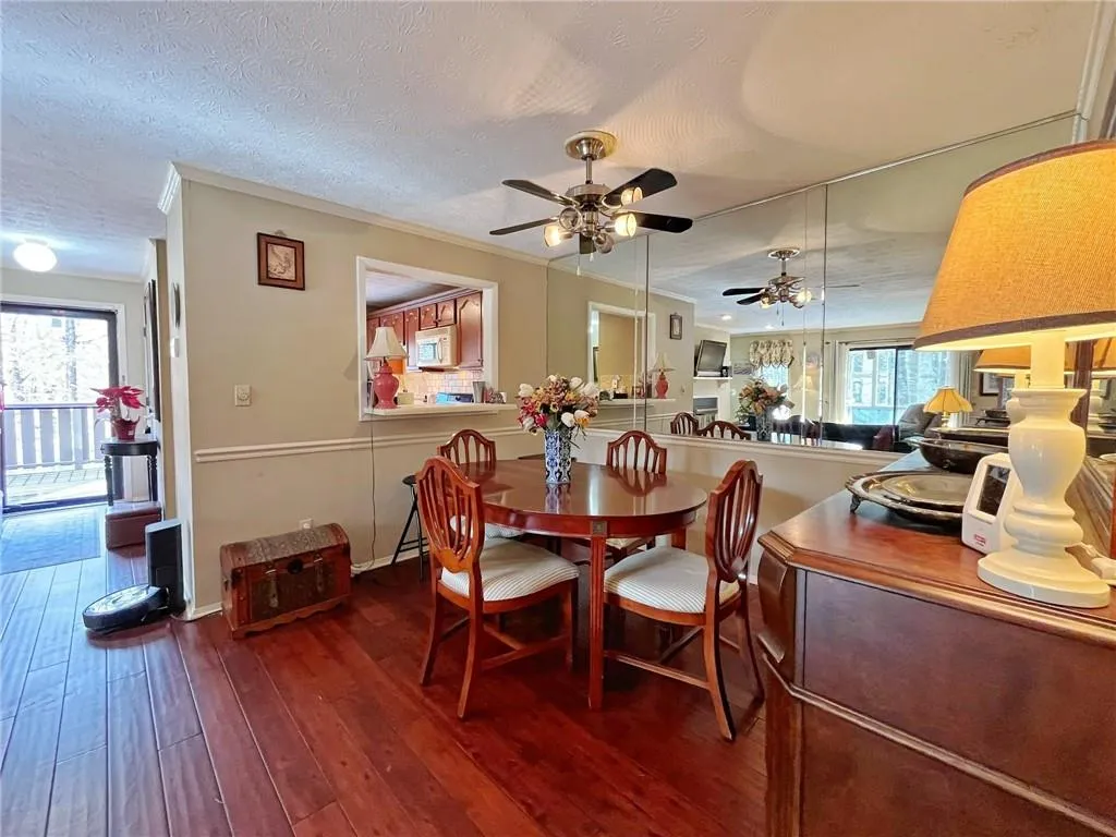 Dining room featuring ornamental molding, dark wood-style flooring, a textured ceiling, and a ceiling fan