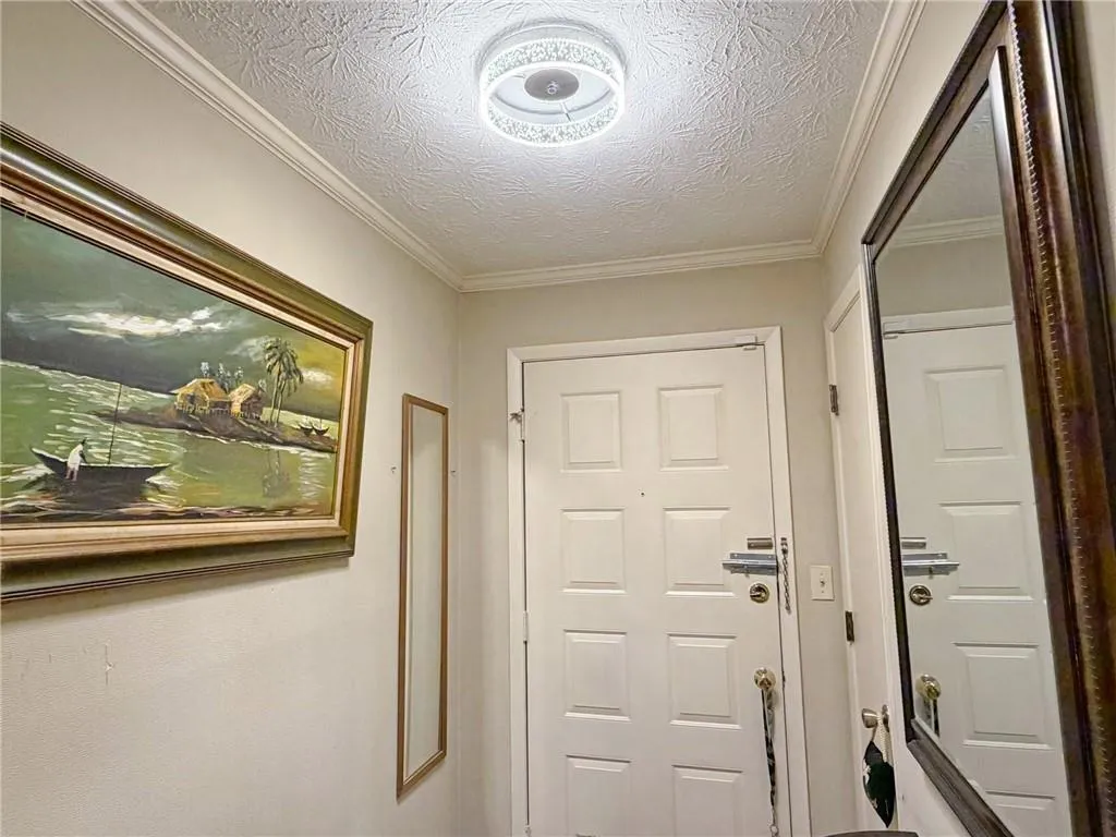 Doorway featuring crown molding and a textured ceiling