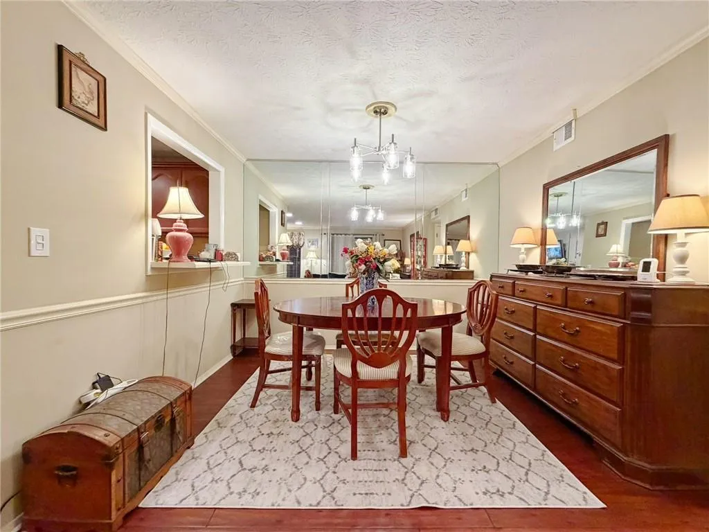 Dining space with ornamental molding, dark wood-type flooring, hanging lights, and a textured ceiling