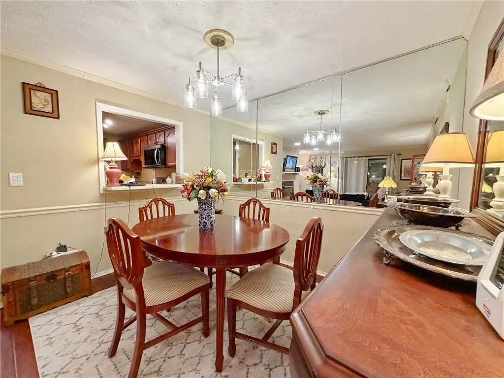 Dining room with light wood-type flooring, crown molding, a textured ceiling, and hanging lights