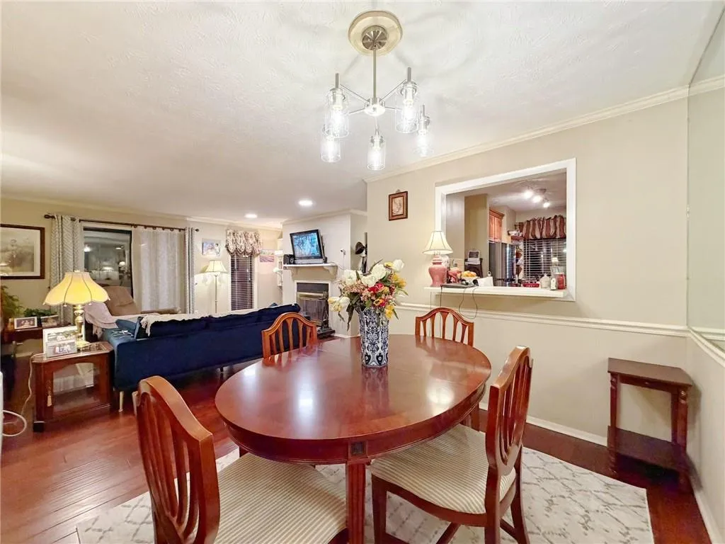 Dining space featuring wood finished floors, a fireplace, crown molding, and recessed lighting