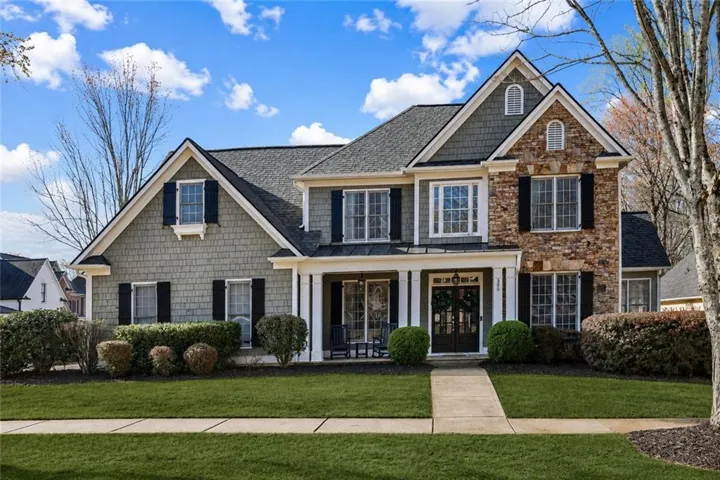 Craftsman-style exterior featuring stone and shake siding, dark shutters, and a covered porch
