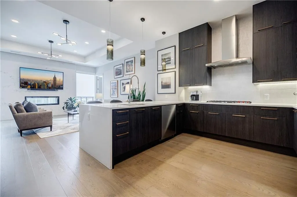 Kitchen with light wood-style floors, gas cooktop, dishwasher, a peninsula, and wall chimney exhaust hood