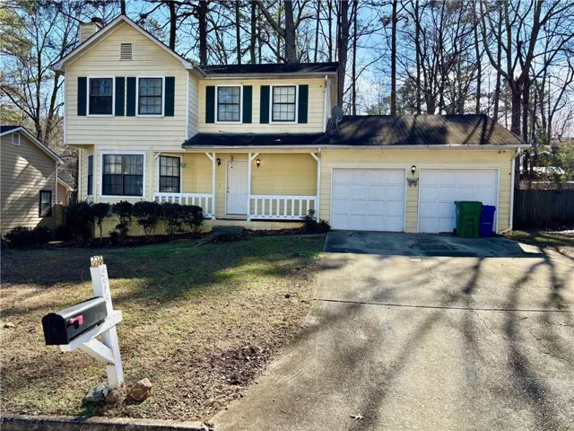 Front of property featuring a garage, covered porch, and a front yard