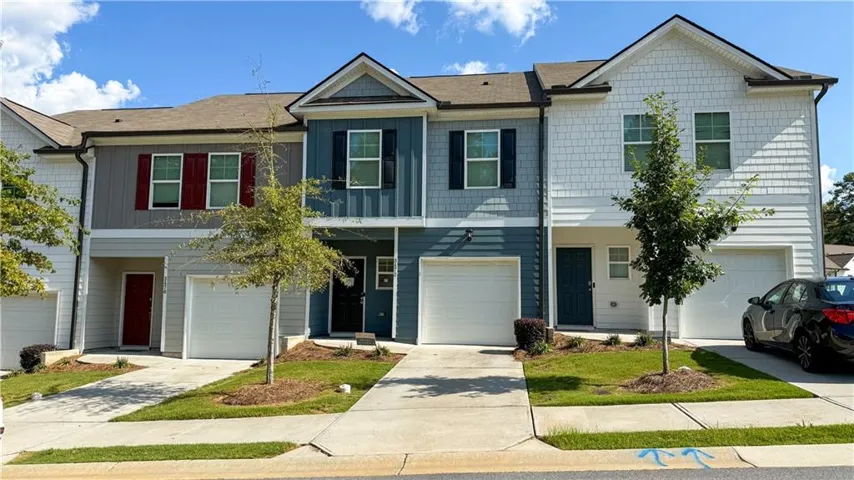 Multi-level townhome featuring a mix of horizontal siding and shake siding, attached garage, and a concrete driveway