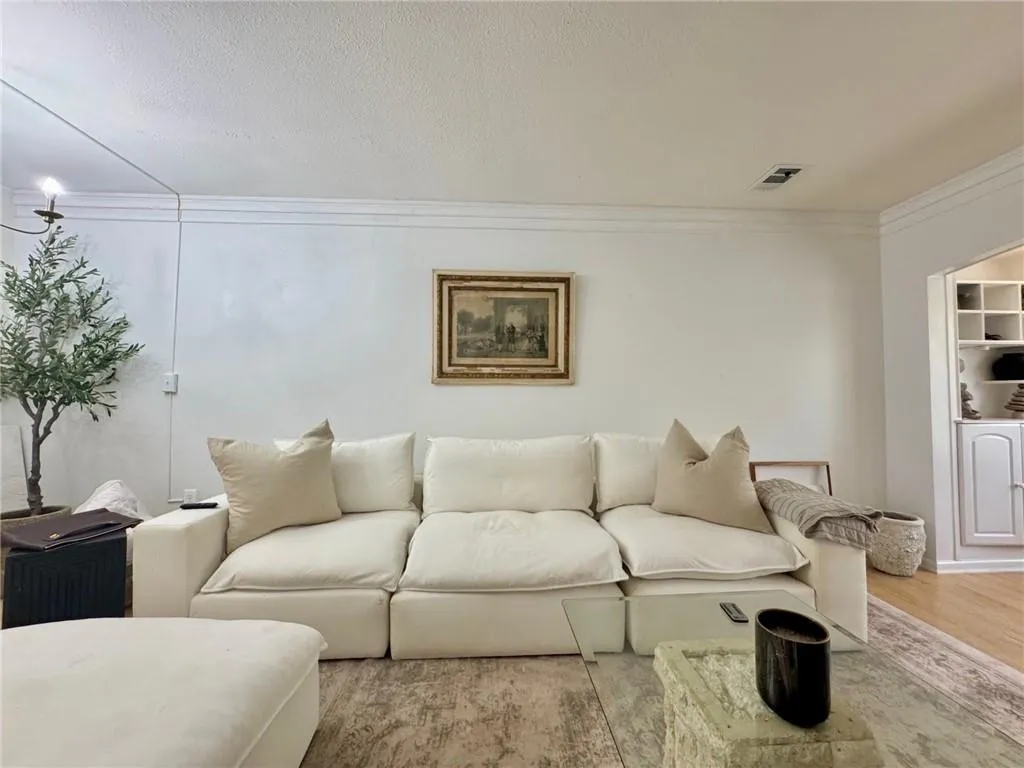 Living area featuring crown molding, wood finished floors, and a textured ceiling