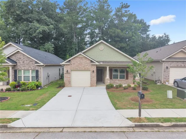 Brick and siding exterior featuring an attached single-car garage, covered entry porch, concrete driveway, and established landscaping