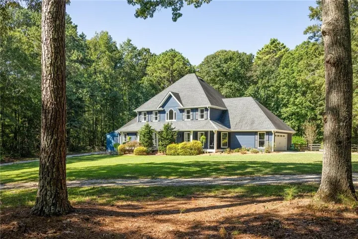 Two-story residence featuring blue siding with white trim, a multi-pitch roof, and an attached two-car garage