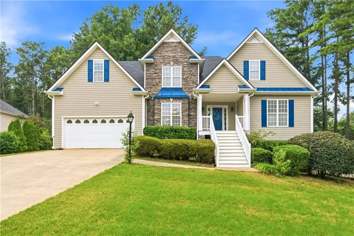 Traditional exterior featuring stone and siding accents, a two-car garage, and a covered porch with white railings