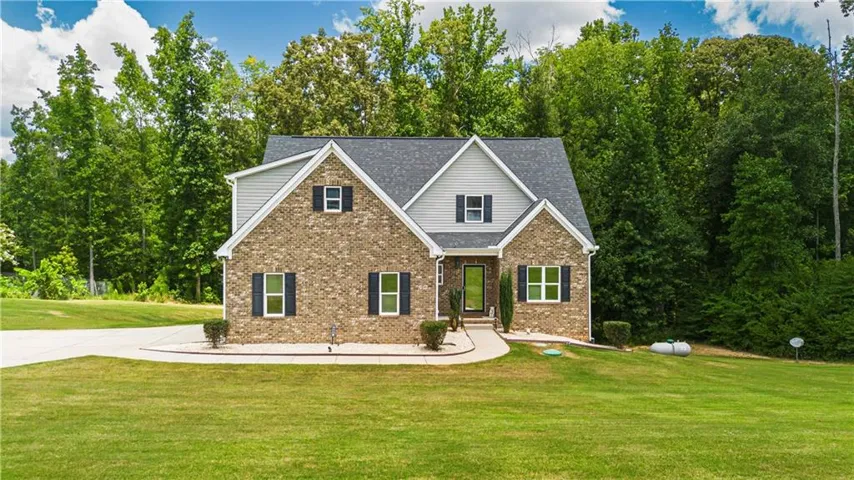 Two-story residence featuring a brick and siding facade with a dark shingle roof