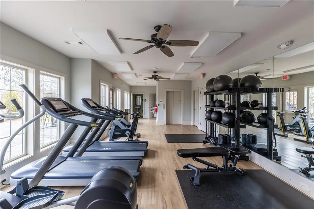 Gym with a ceiling fan, wood finished floors, and attic access