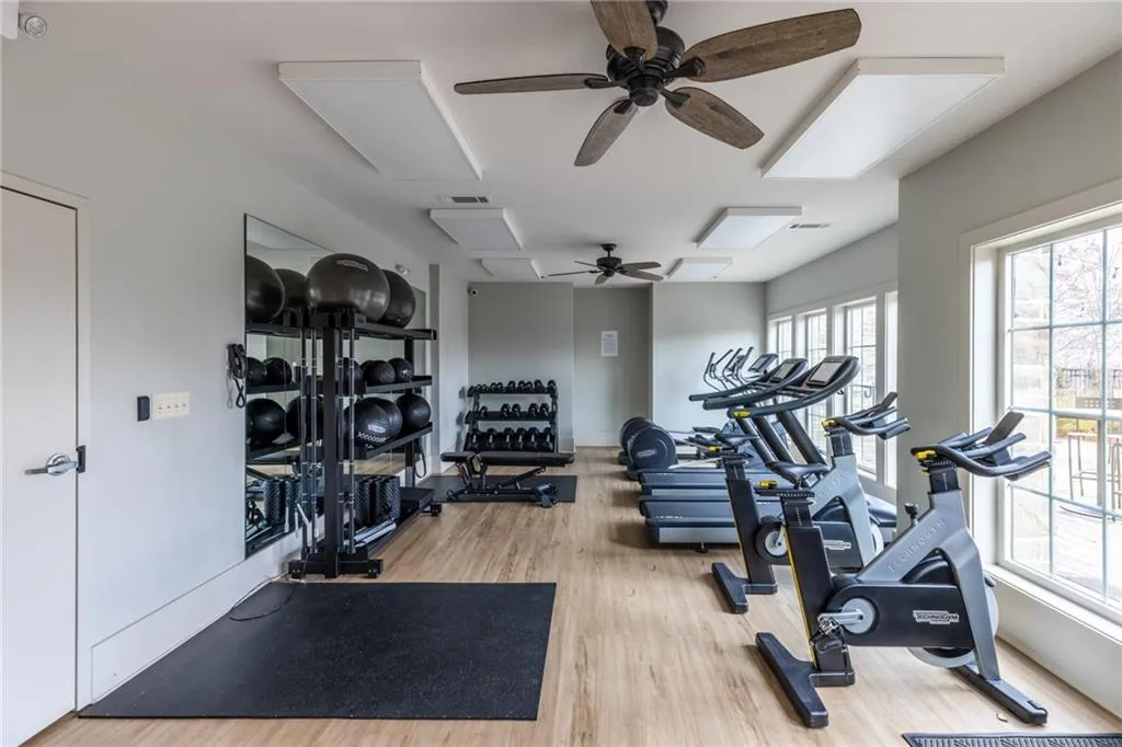 Gym with wood finished floors, a ceiling fan, and attic access