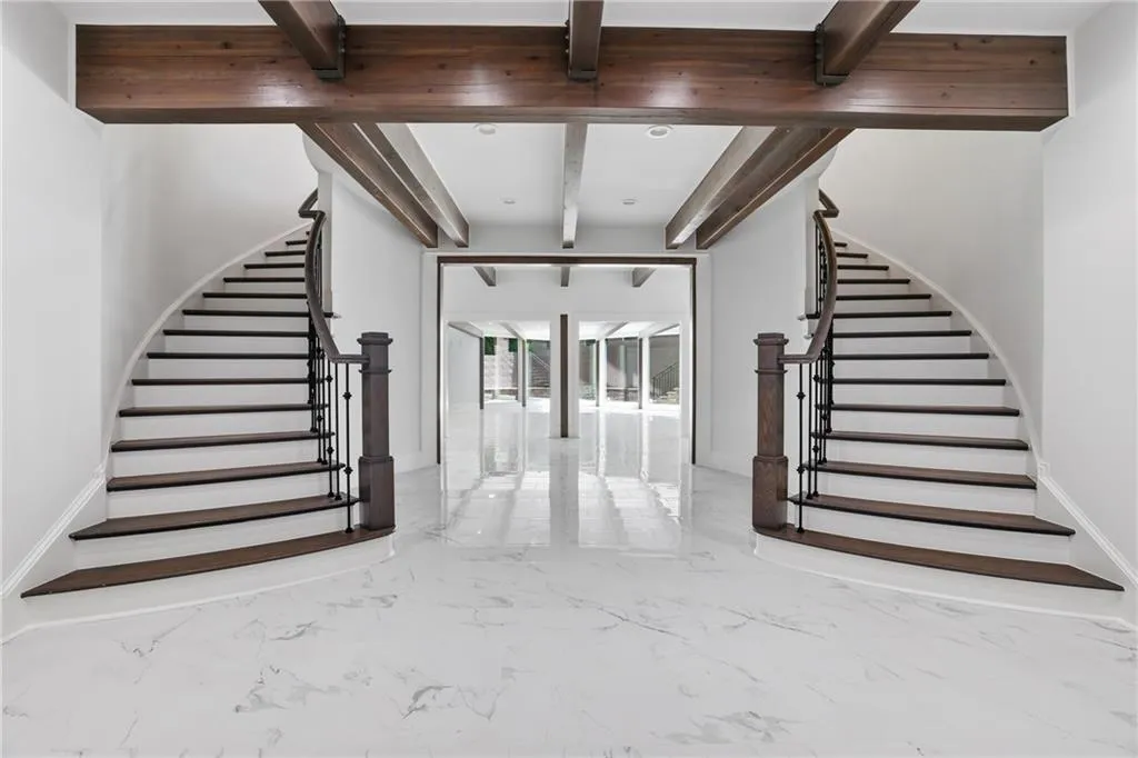 Grand entryway featuring a dual curved staircase with dark wood treads and wrought iron balusters