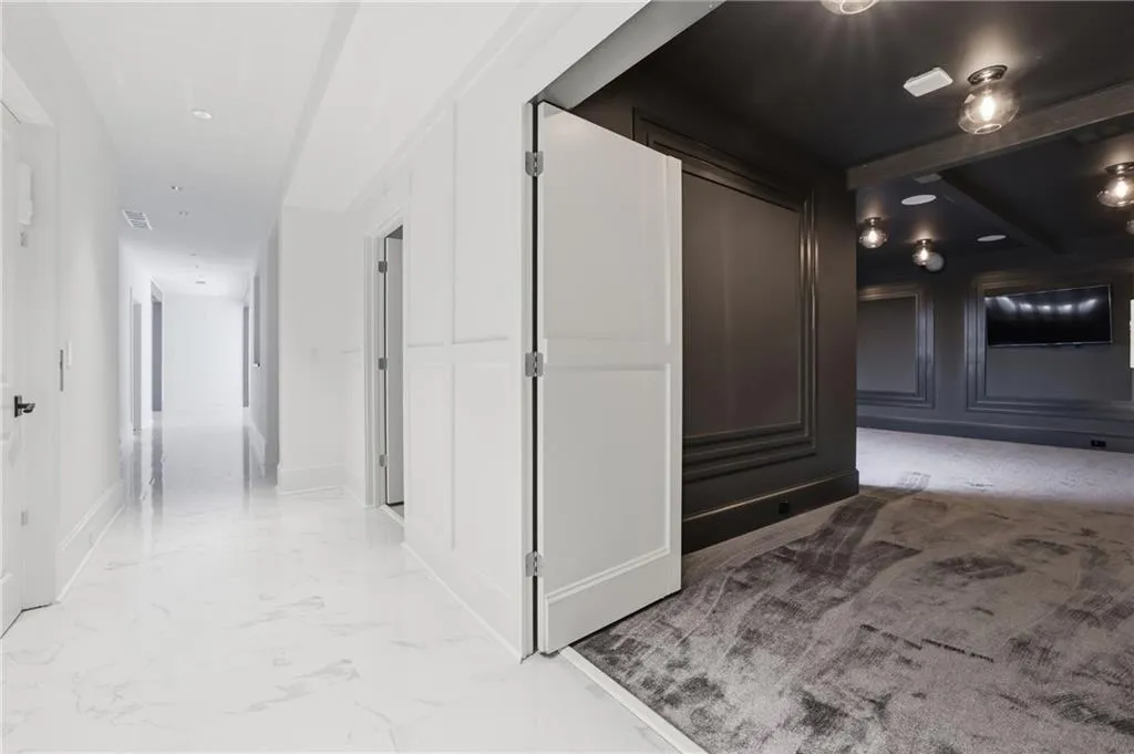 White hallway with high-gloss flooring leading to a darker room with textured carpeting