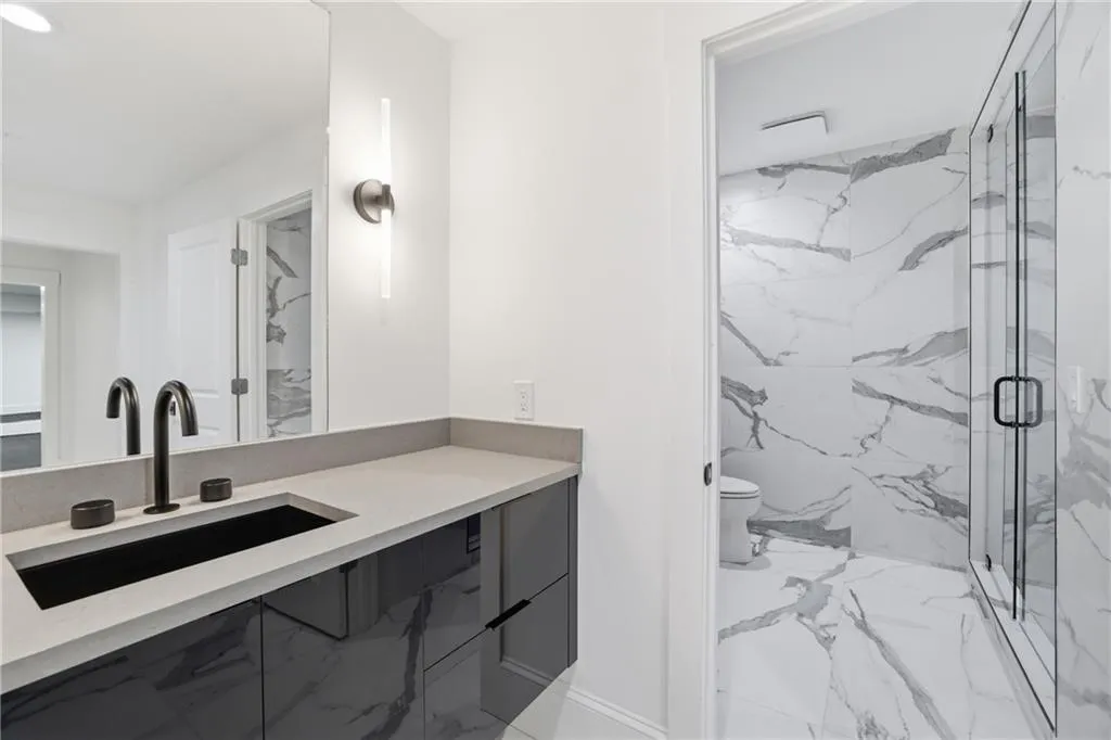 Sleek vanity with a dark integrated sink, matte black fixtures, and a light-toned countertop