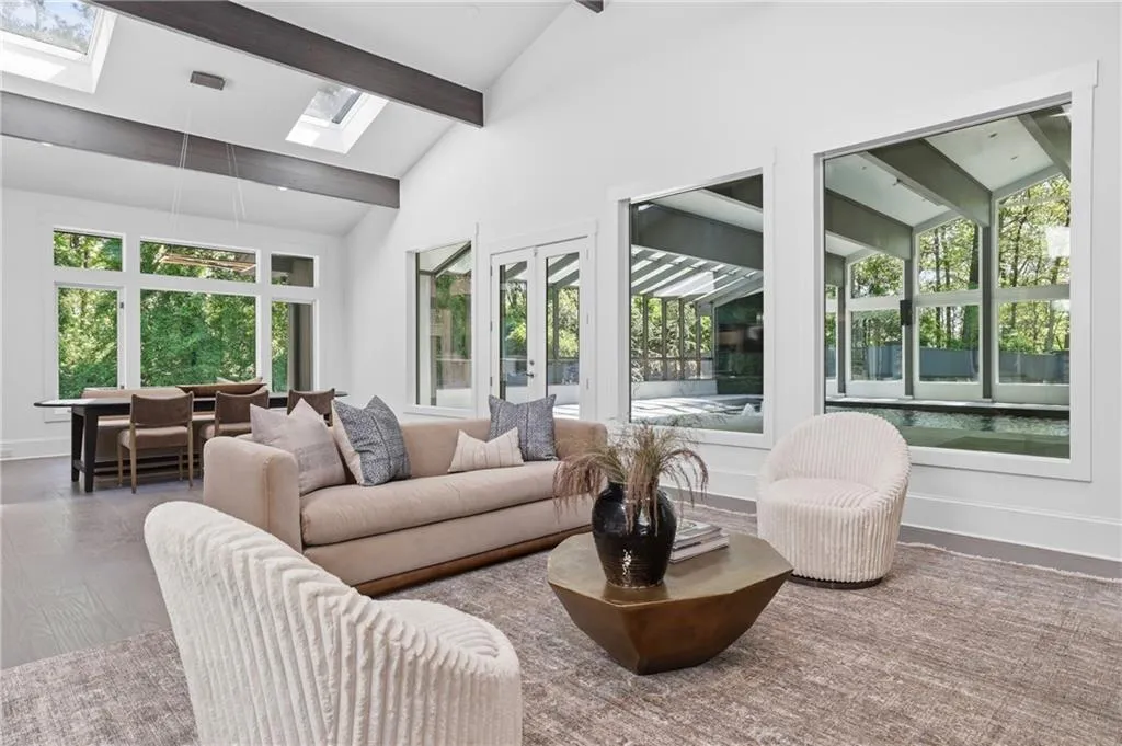 High vaulted ceiling with exposed beams, multiple skylights, and large windows offering abundant natural illumination
