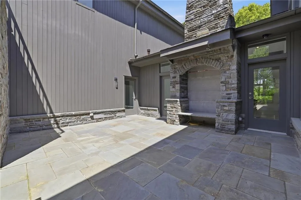 Expansive stone patio featuring a built-in stone bench, a stone archway, and a stone chimney structure