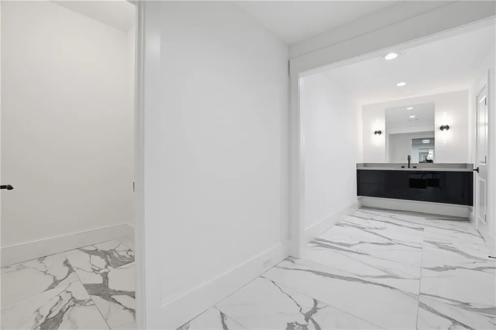 Hallway featuring white walls and large format porcelain tile flooring with gray veining