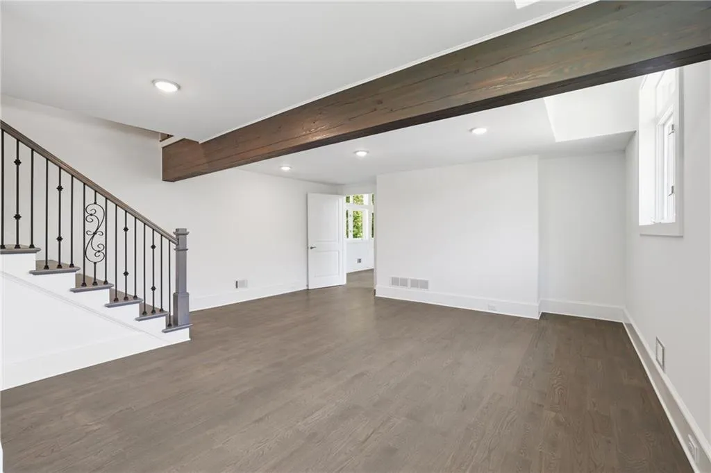 Spacious room featuring wood-finish flooring, white walls, and recessed lighting