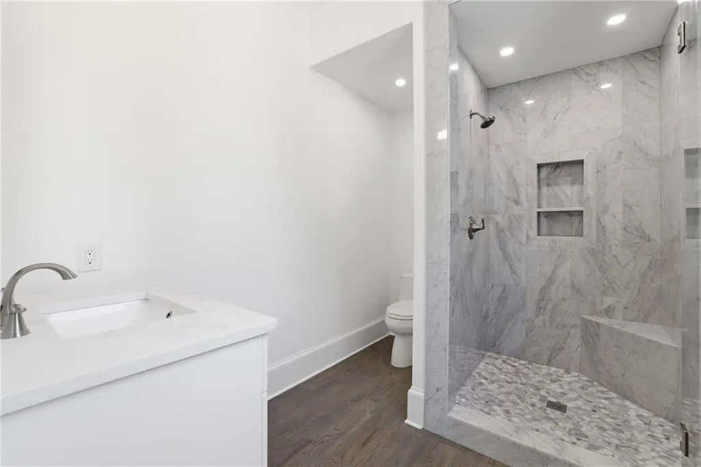 Contemporary bathroom featuring a spacious walk-in shower with marble-look tile, built-in bench, and dual recessed niches
