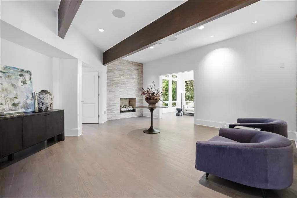 Spacious interior room featuring wood-finish flooring, vaulted ceilings with exposed beams, and recessed lighting