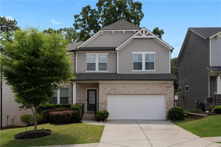 Two-story residence featuring a brick facade, gray horizontal siding, and a white garage door