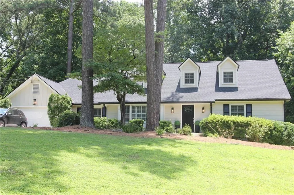 Cape cod-style house with a front yard, an attached garage, and roof with shingles