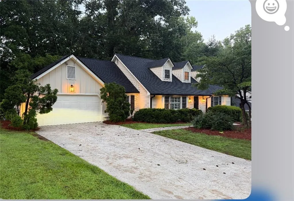 New england style home with driveway, board and batten siding, a shingled roof, and a front yard