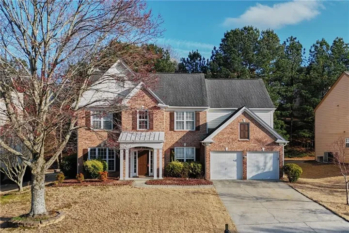 View of front of property featuring driveway, a garage, brick siding, and a front yard