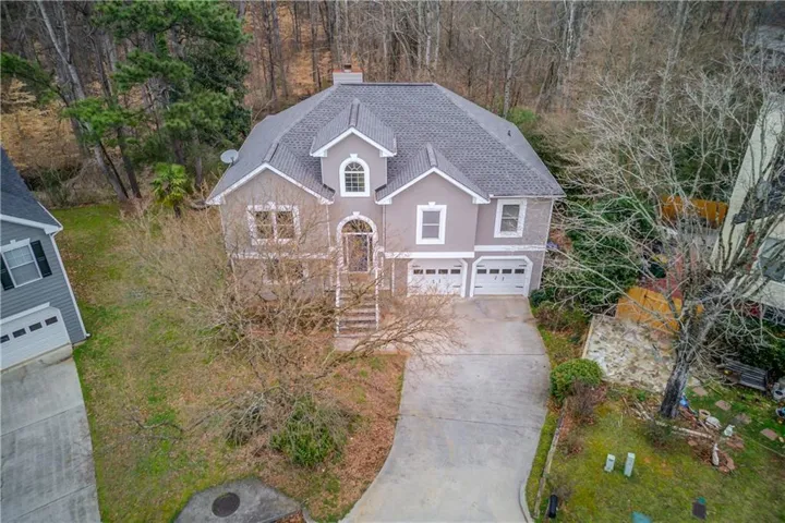 View of front of property with roof with shingles, a garage, concrete driveway, stucco siding, and a chimney