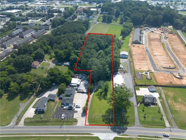 Expansive aerial view of a substantial land parcel, outlined in red, featuring significant tree coverage