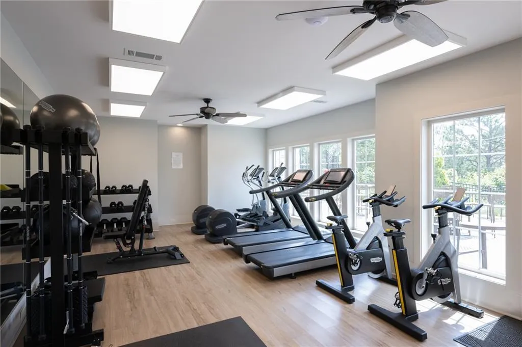 Workout area with a ceiling fan and light wood-style flooring
