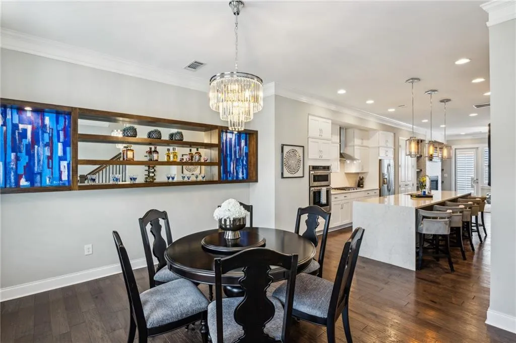 Dining room featuring a chandelier, ornamental molding, dark wood flooring, and recessed lighting