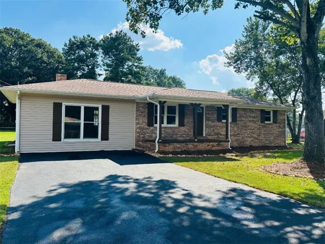 Brick and siding exterior, asphalt driveway, covered entry porch, and mature trees