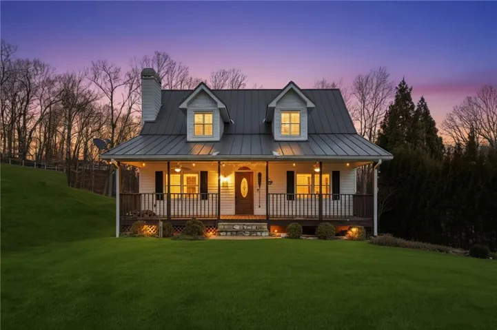 Modern inspired farmhouse featuring a front yard, a standing seam roof, a chimney, a porch, and a metal roof