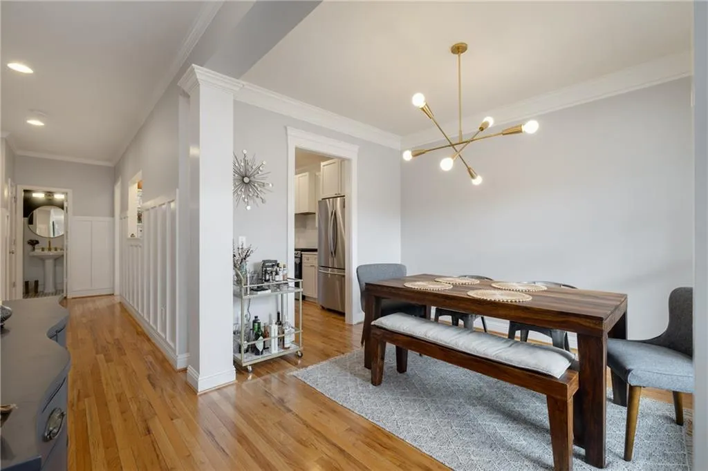 Dining space with crown molding, ornate columns, recessed lighting, light wood-type flooring, and an inviting chandelier