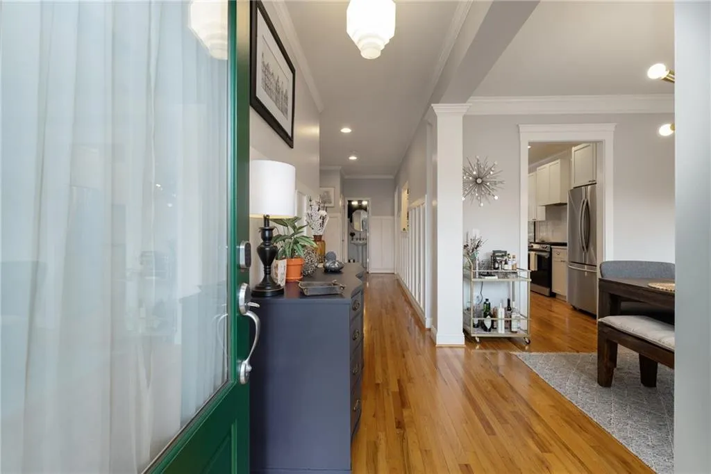 Corridor with decorative columns, light wood-type flooring, recessed lighting, and crown molding