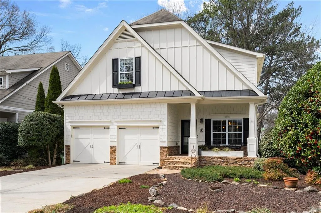 View of front of house featuring driveway, a standing seam roof, board and batten siding, metal roof, and a porch