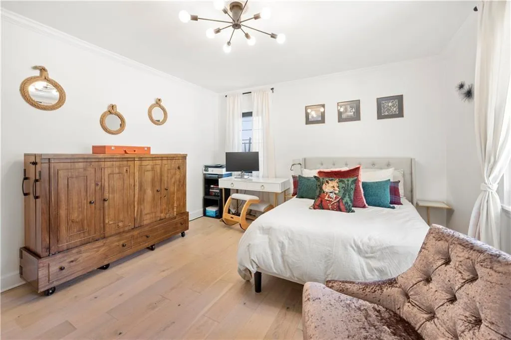 Bedroom with crown molding, light wood-style flooring, and a chandelier