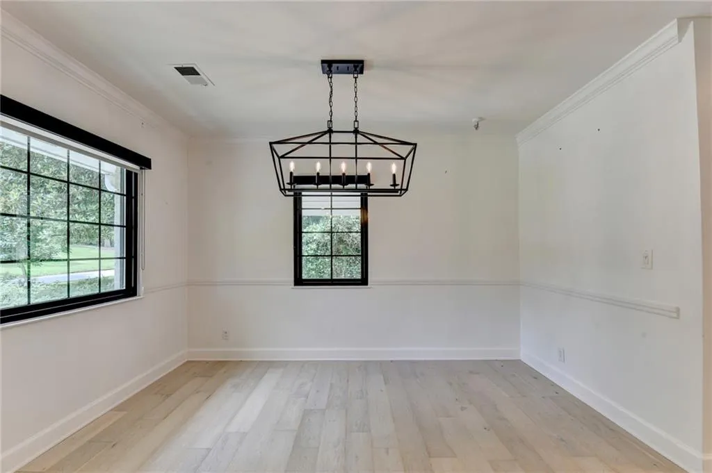 Unfurnished dining area with light wood-style floors, ornamental molding, and a chandelier