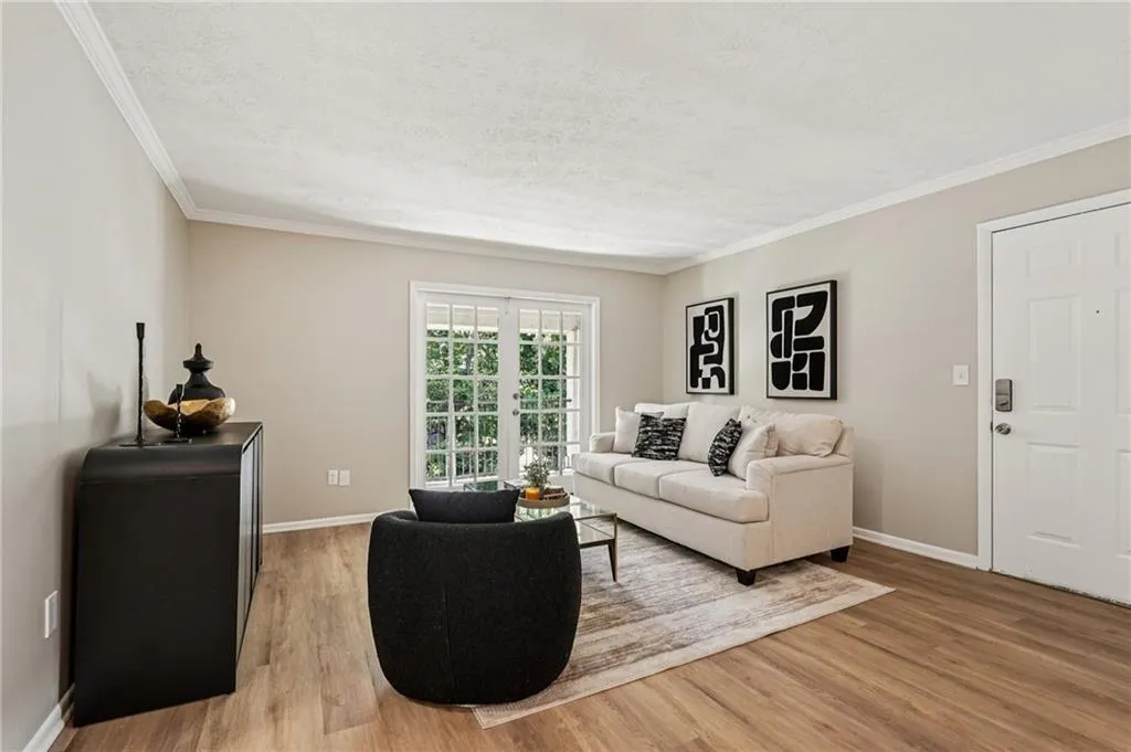 Living room with light wood-style flooring, ornamental molding, and a textured ceiling