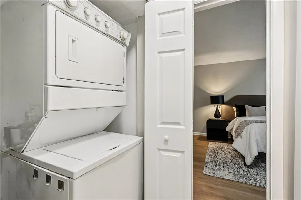 Laundry room with wood finished floors and stacked washing machine and dryer