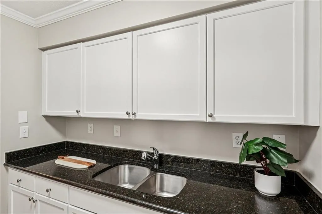 Kitchen featuring white cabinets, dark stone countertops, and crown molding